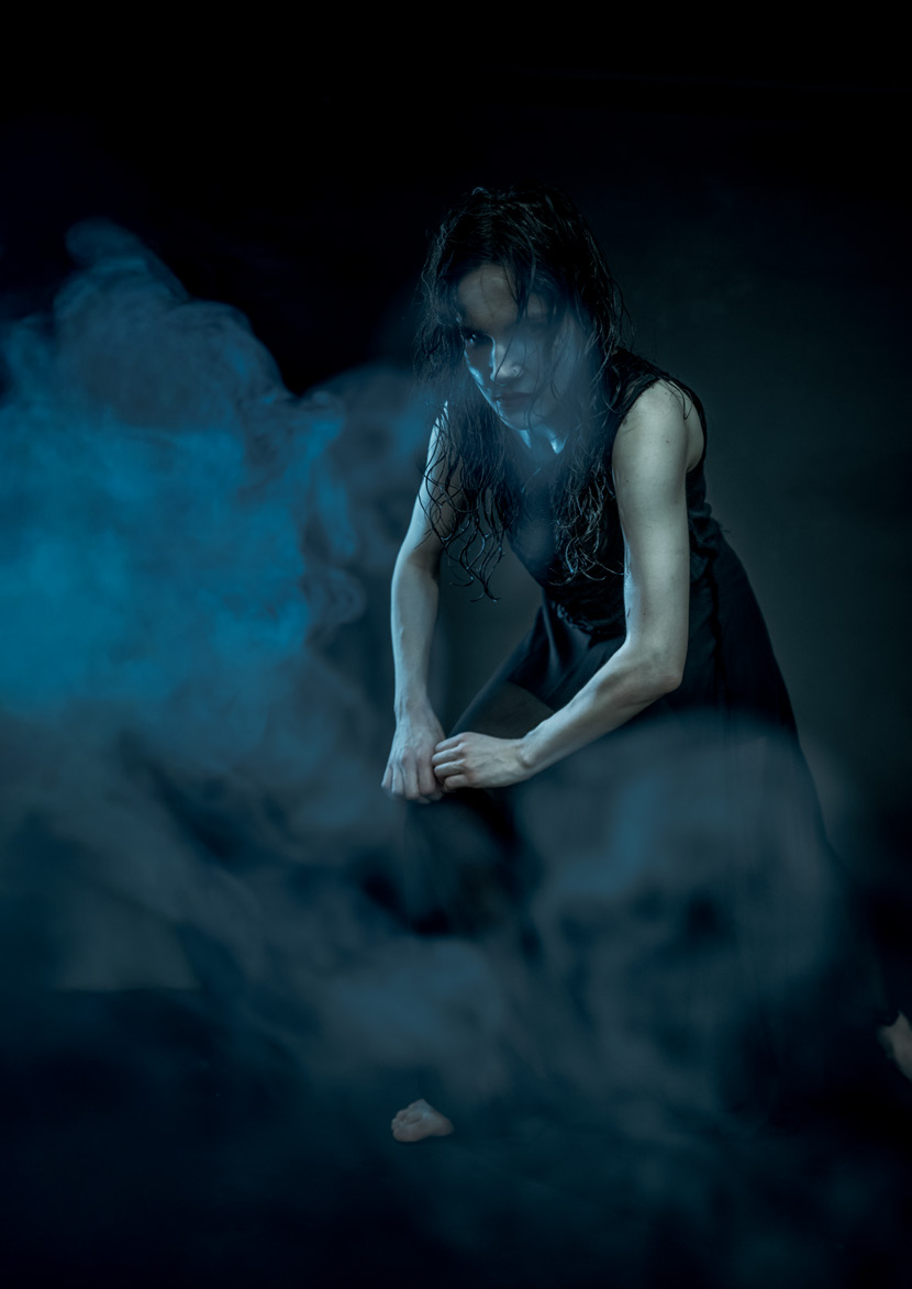 A solo dancer emerging from blue stage haze
